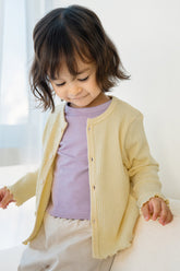 Smiling toddler in Avauma butter yellow cardigan and soft cotton leggings, playful baby girl spring outfit